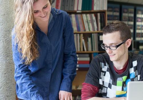 Deux étudiants regardent un livre à la bibliothèque