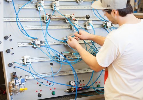 Un étudiant en Technologie de la mécanique industrielle tient des câbles sur un panneau