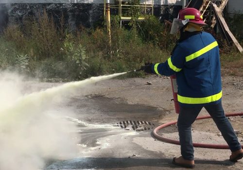 Un étudiant vêtu d'un manteau et casque de pompier en pratique d'arrosage