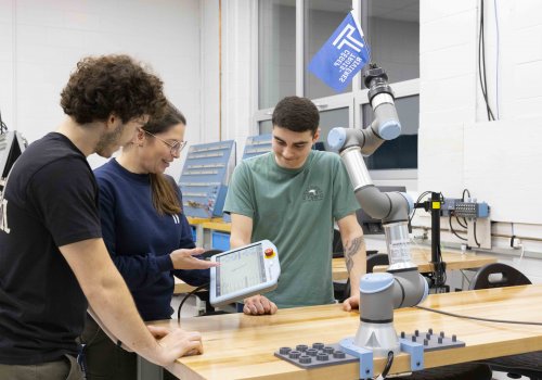 Une enseignante montrant un projet sur une tablette électronique à deux étudiants